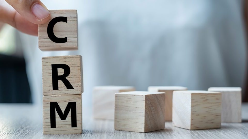 Business woman hand holding wooden cube with crm